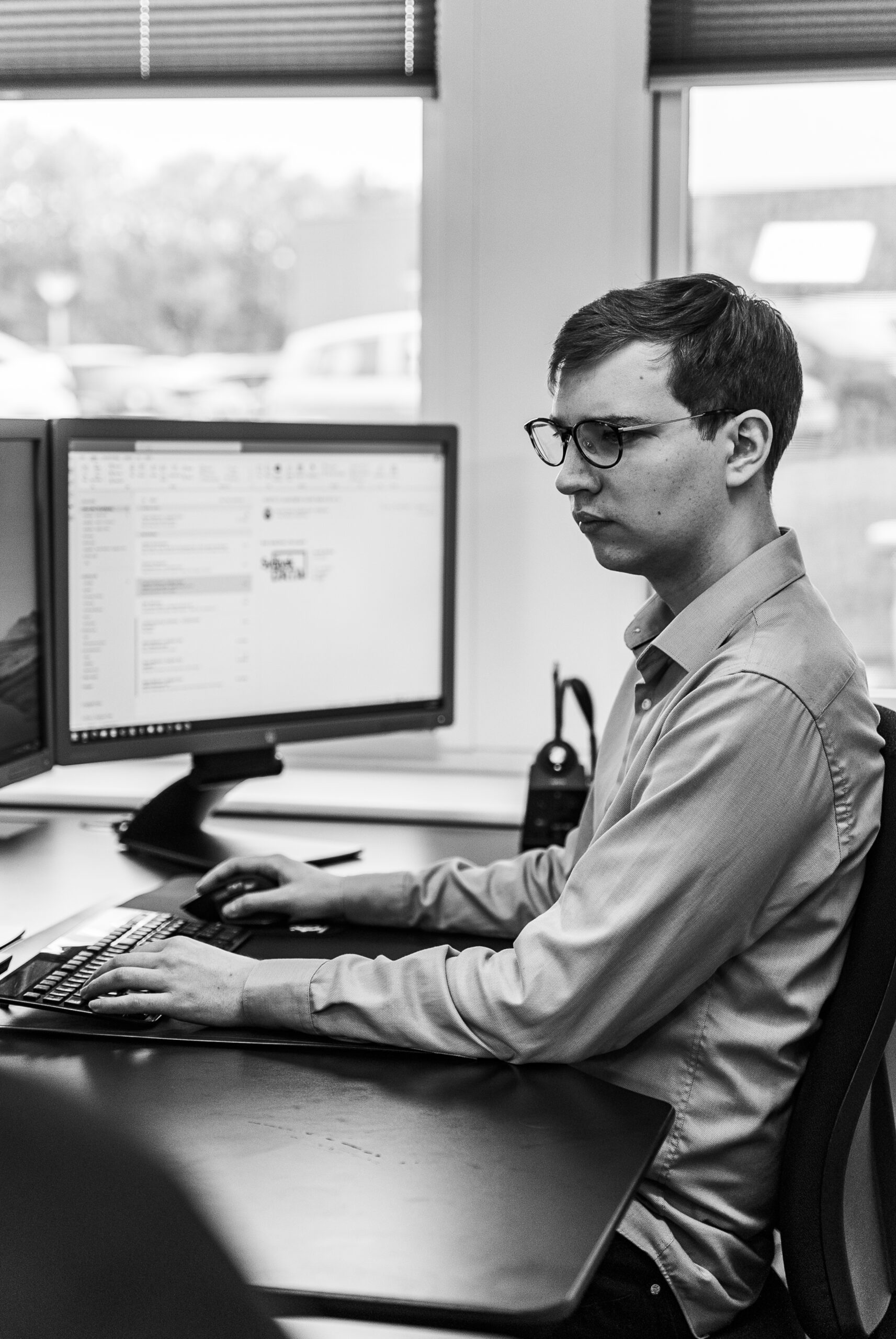 Mand, der sidder og arbejder ved computer med outlook åbent, som er et af Microsoft 365 produkterne